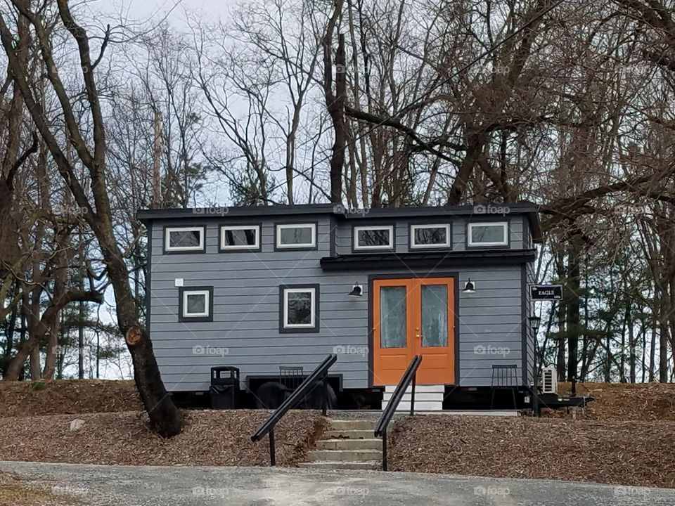 Tiny house in gray with black trim and orange front door