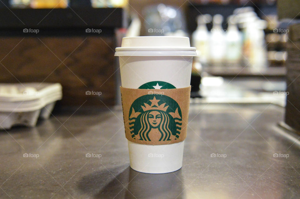 A Starbucks coffee cup sitting on a counter at a Starbucks store