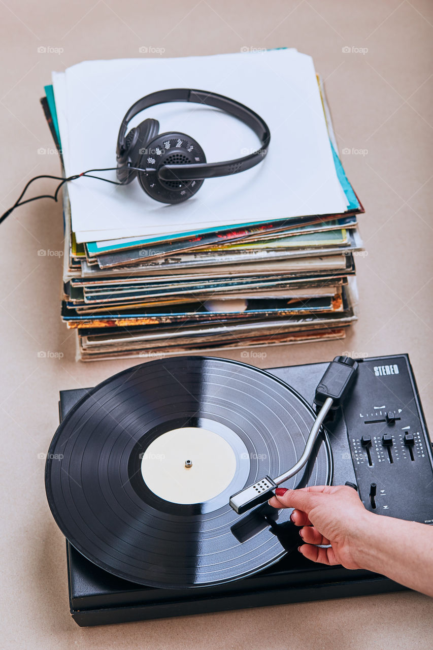 Stack of many black vinyl records, turntable vinyl player and headphones put on the stack. Classic stereo set. Candid people, real moments, authentic situations