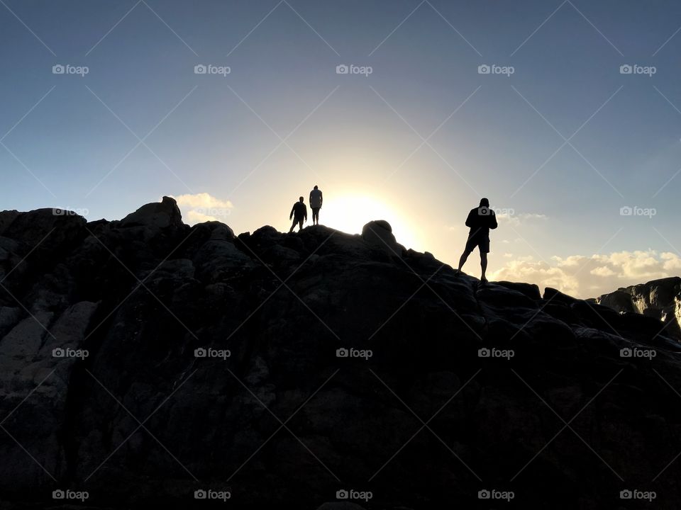 People climbing a hill at sunset