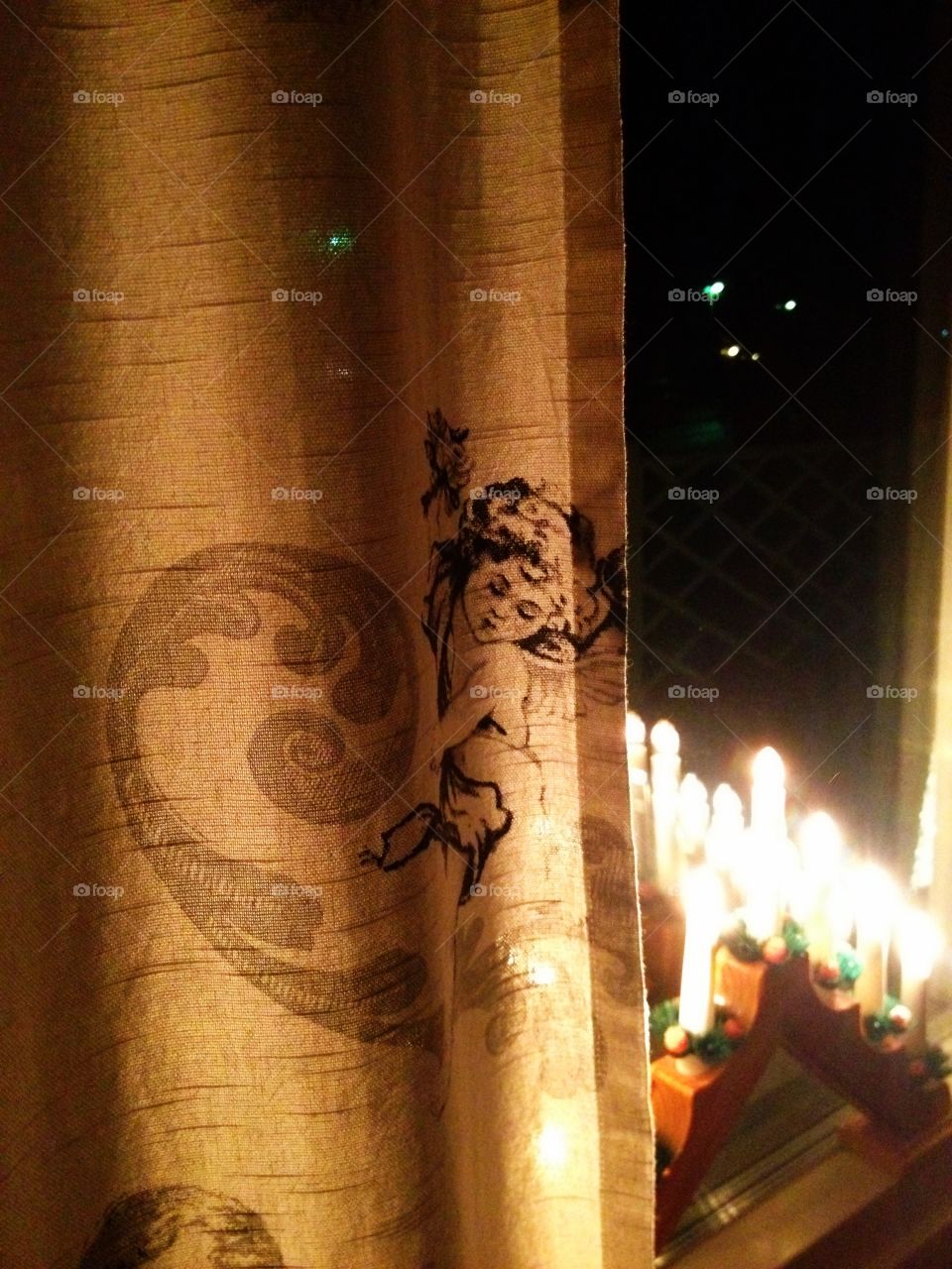 When the angels fall. White curtain with angel print, window and candles