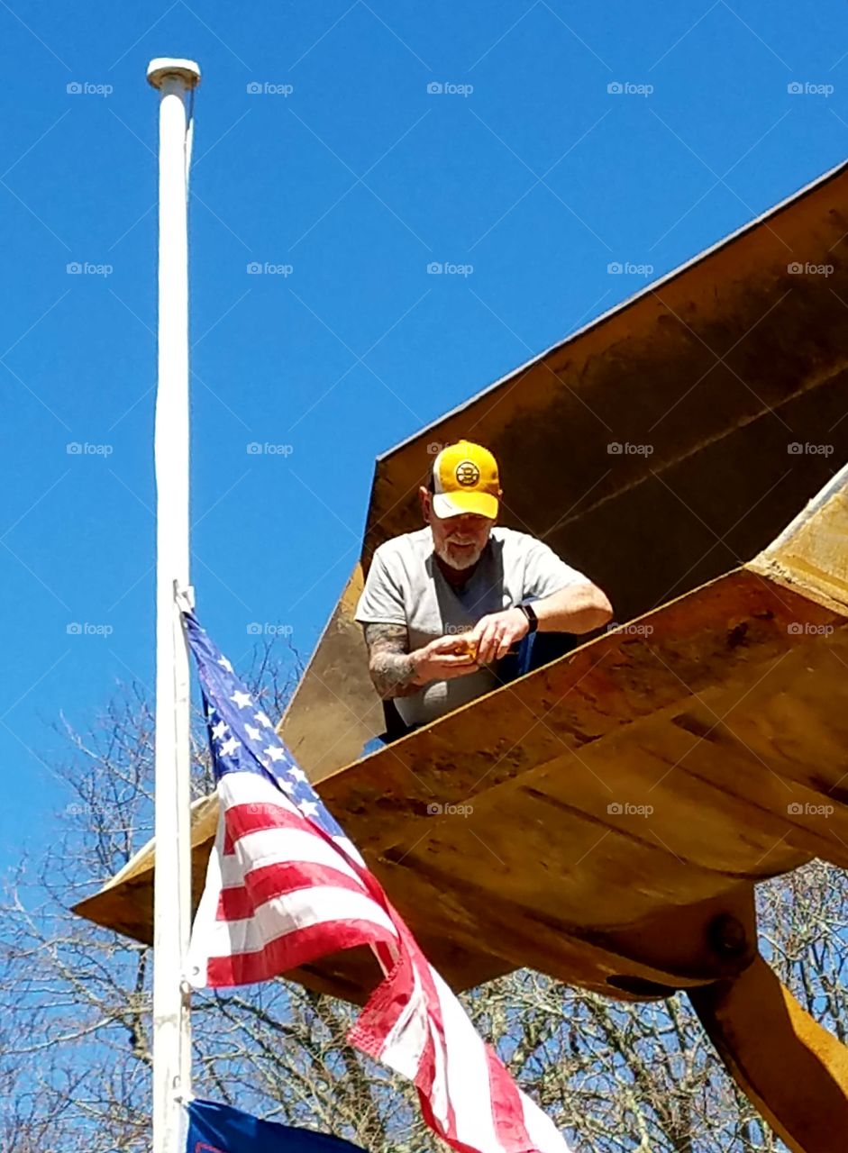 Repair to American Flagpole made by adding new brass topper. Man in bucket loader safety reaches flagpole top. American Flag 🇺🇸 lowered during the repair.