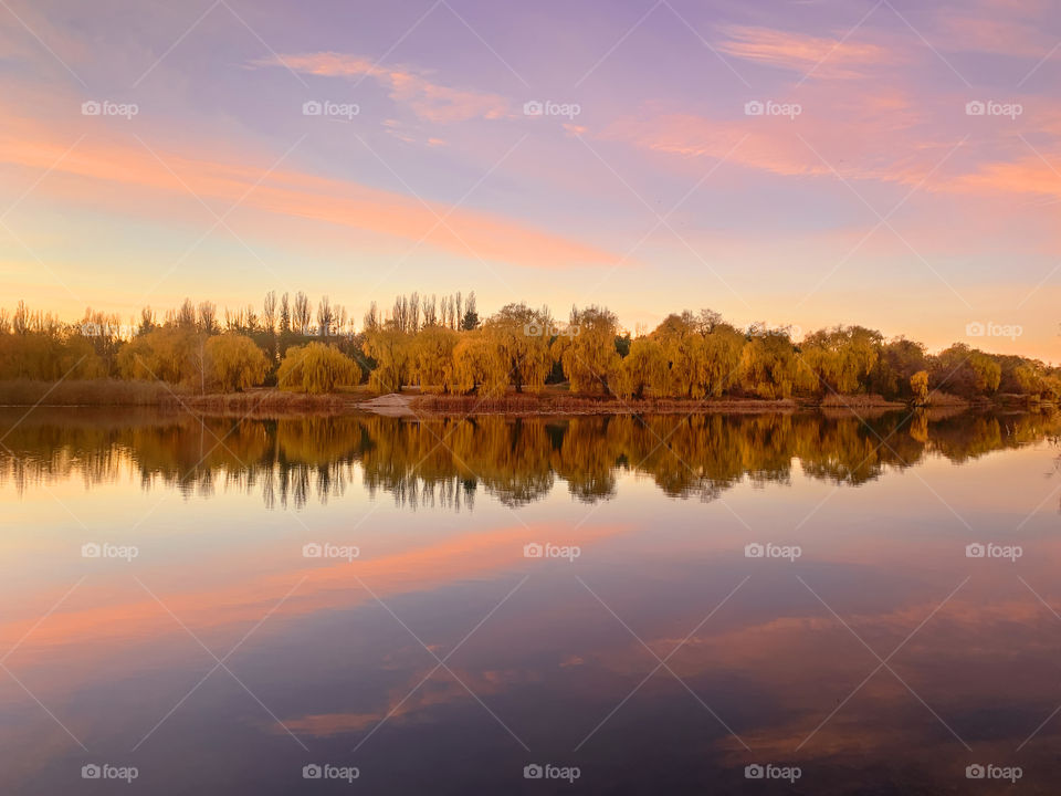 Symmetrical reflection of autumn trees over the lake at sunset 