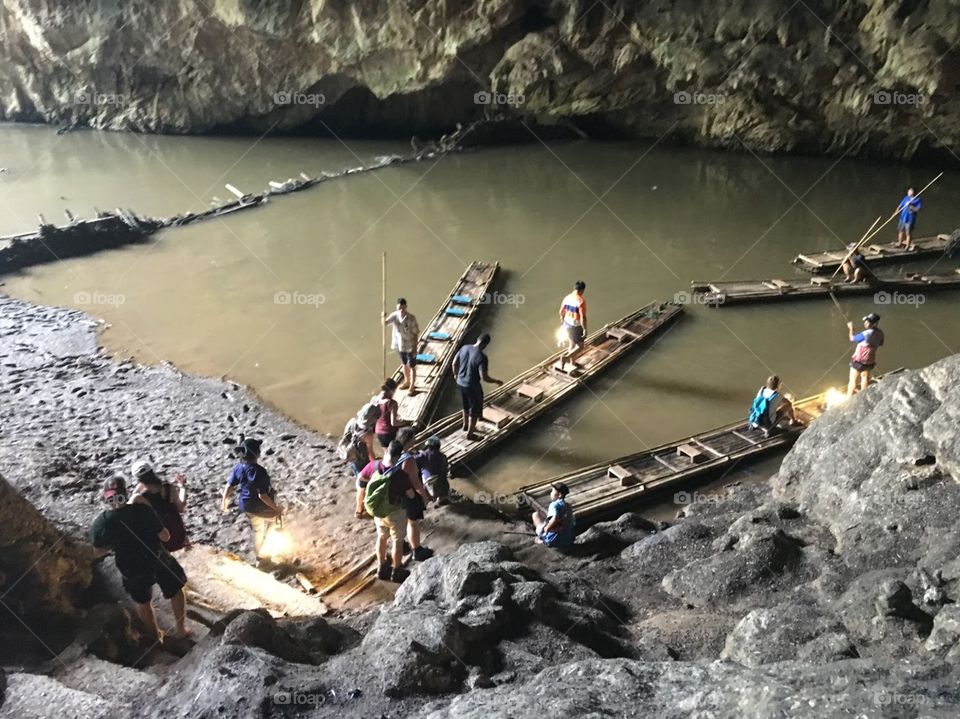 Taking bamboo rafts along the river that went through the cave to get to the other side to continue exploration. 
