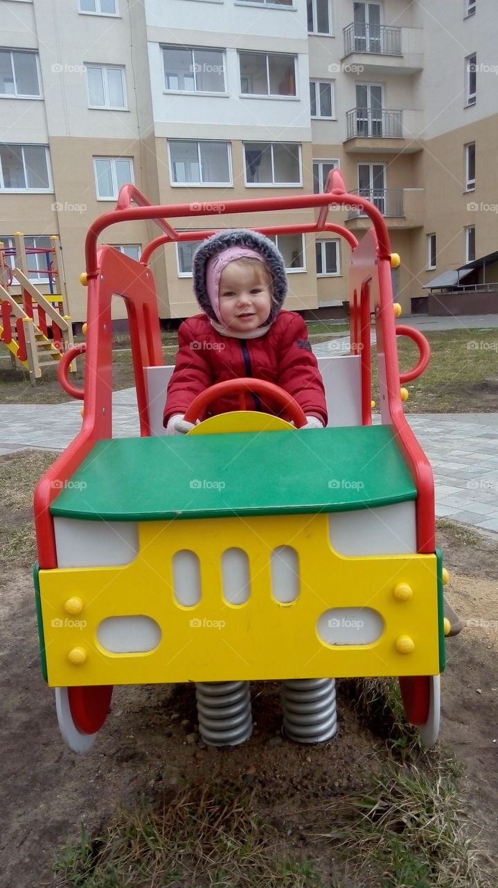 Cute little girl sitting in toy car