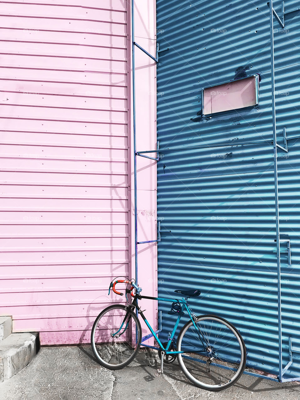 Bicycle standing in front of a blue and pink pastel wall background 