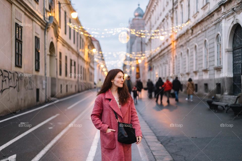 Beautiful woman wearing a pink coat and wandering the city streets.