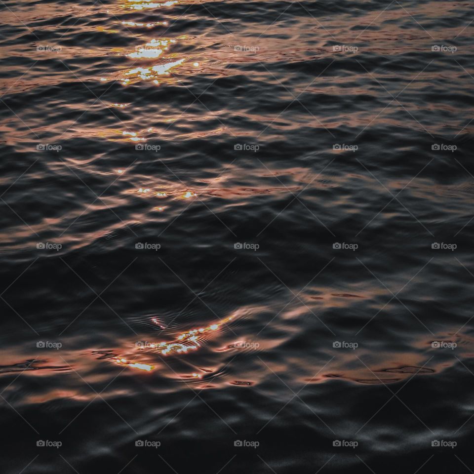 Small waves reflect the rays of the sunset.  Aesthetics of water