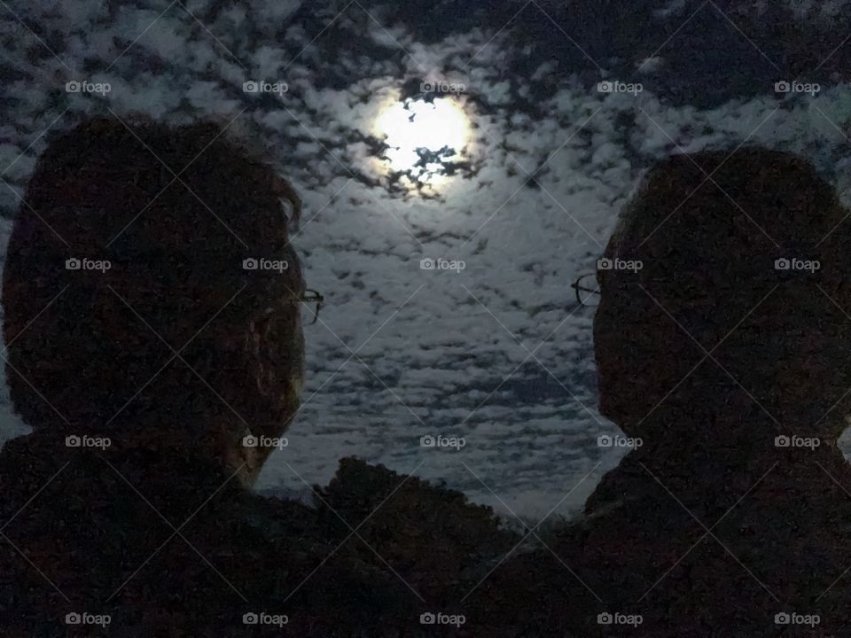 Bright moon behind the clouds, two men gazing at the moon