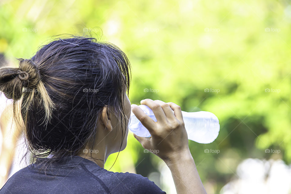 The hands of a woman holding a bottle of water After exercise.