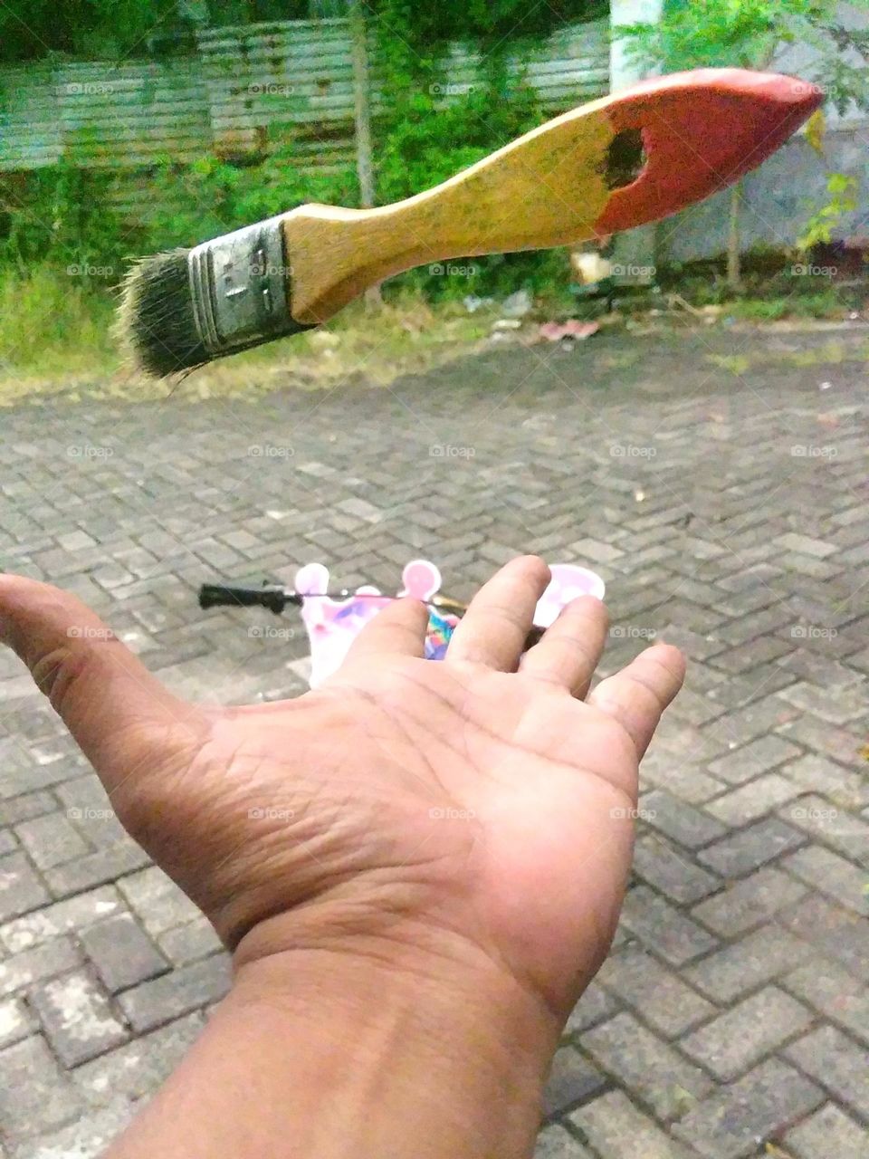 Hand and paintbrush on yard