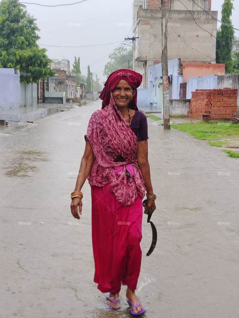 enjoy rain a village women. she return at her home from work in field