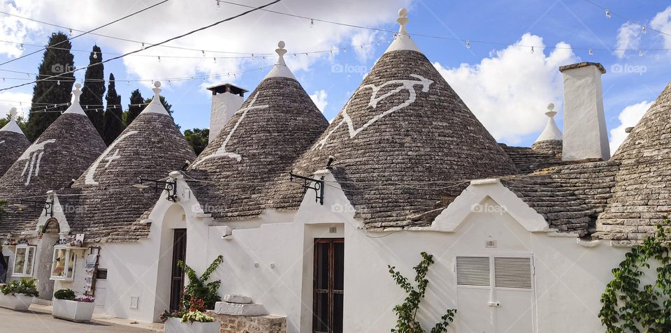 Beautiful white stone houses of Trulla with gray roofs and drawings on them in Alberabello Italy, close-up side view.