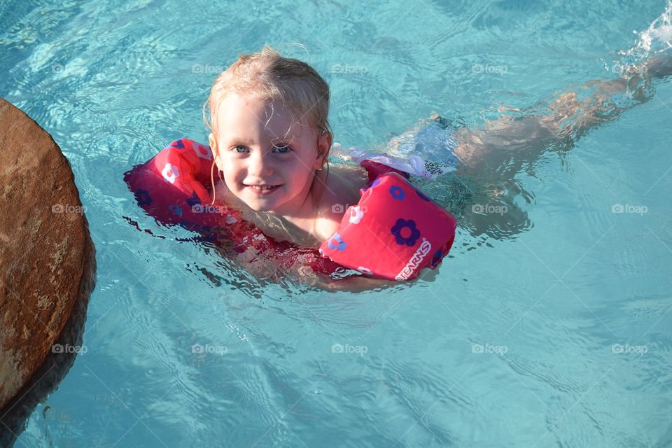 Toddler girl swimming in her floatie
