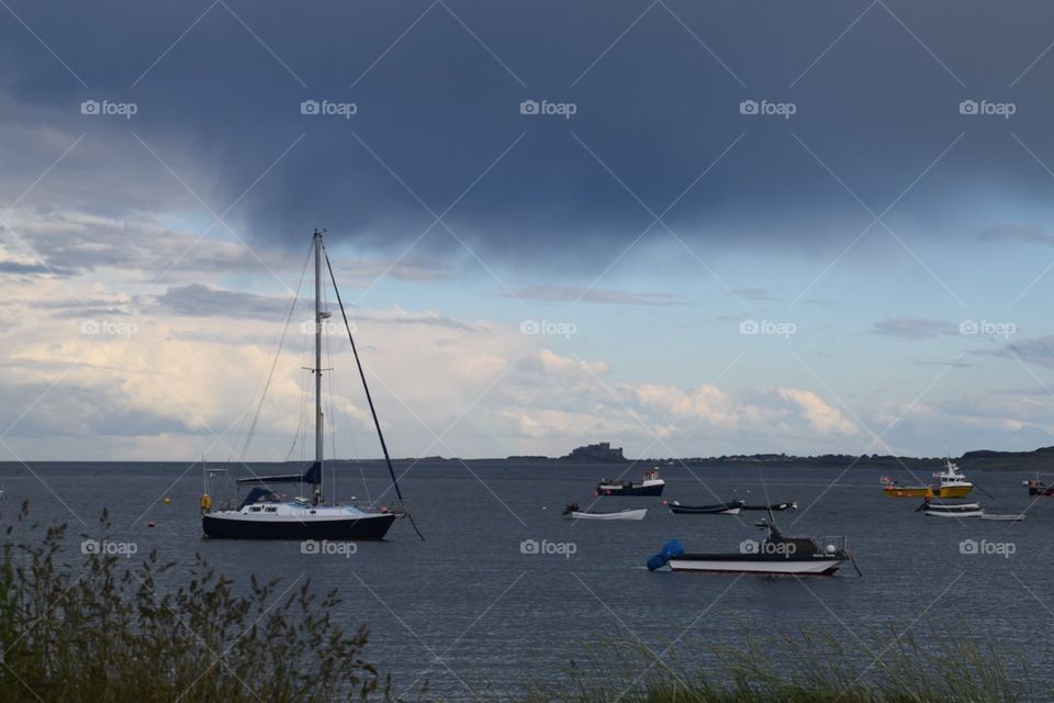 Boats in a harbour with grey and blue sky and grey sea