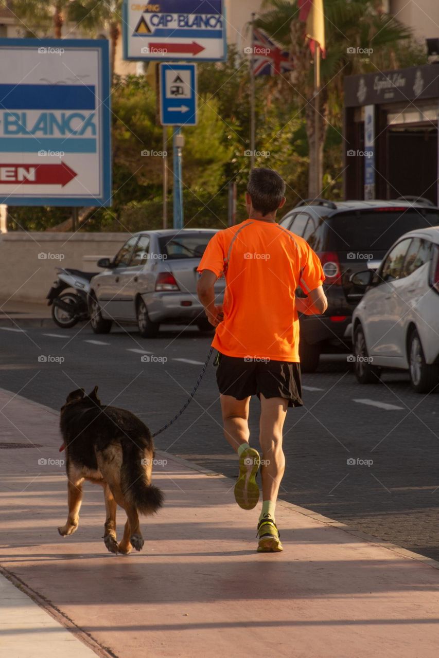 A man taking the dog out for a jog