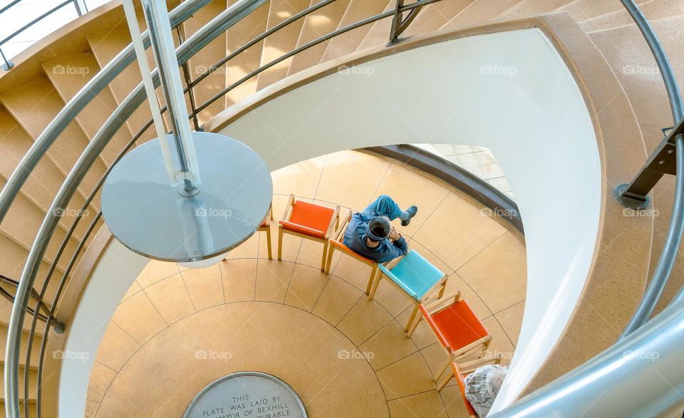 Colourful chairs viewed from above through curved staircase.