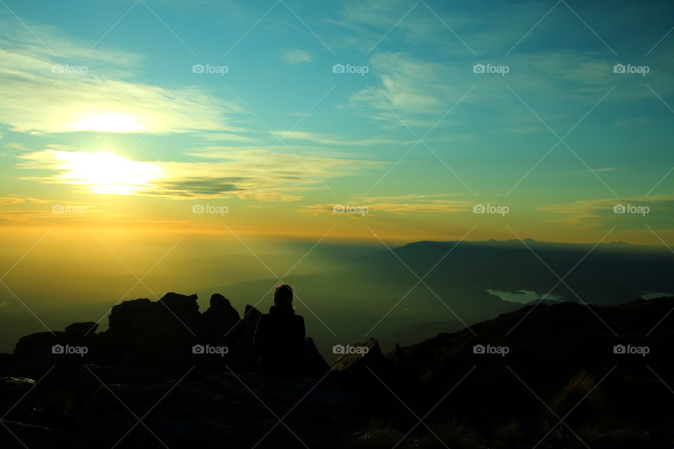 sitting looking the valley. woman relaxed sitting at top mountains at sunset