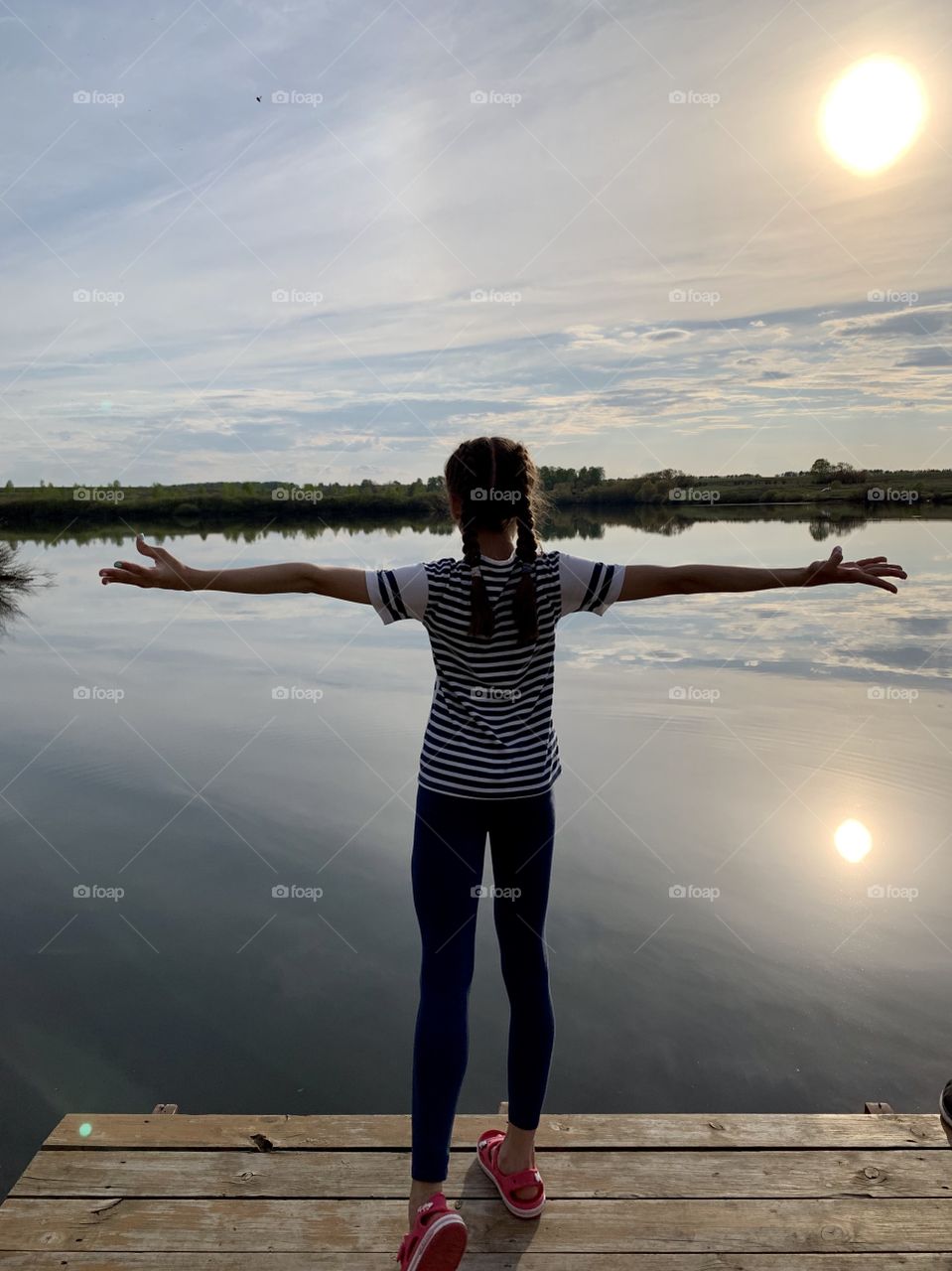 Hello summer! girl on the river bank on the background of nature and sunset.
