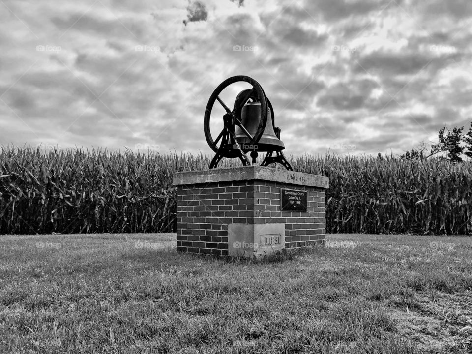 Landmark bell from 1859 in Noir with cornfield background and cloudy sky