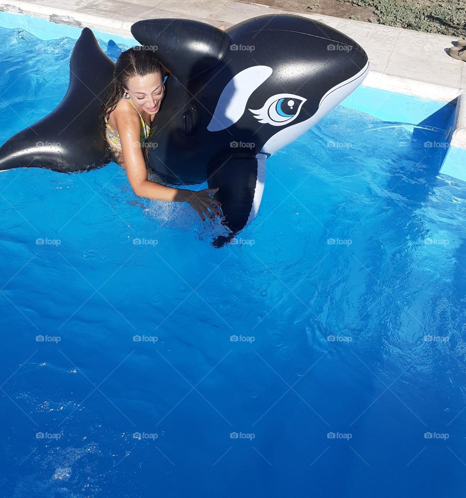 la chica juega divertida con la ballena en la piscina