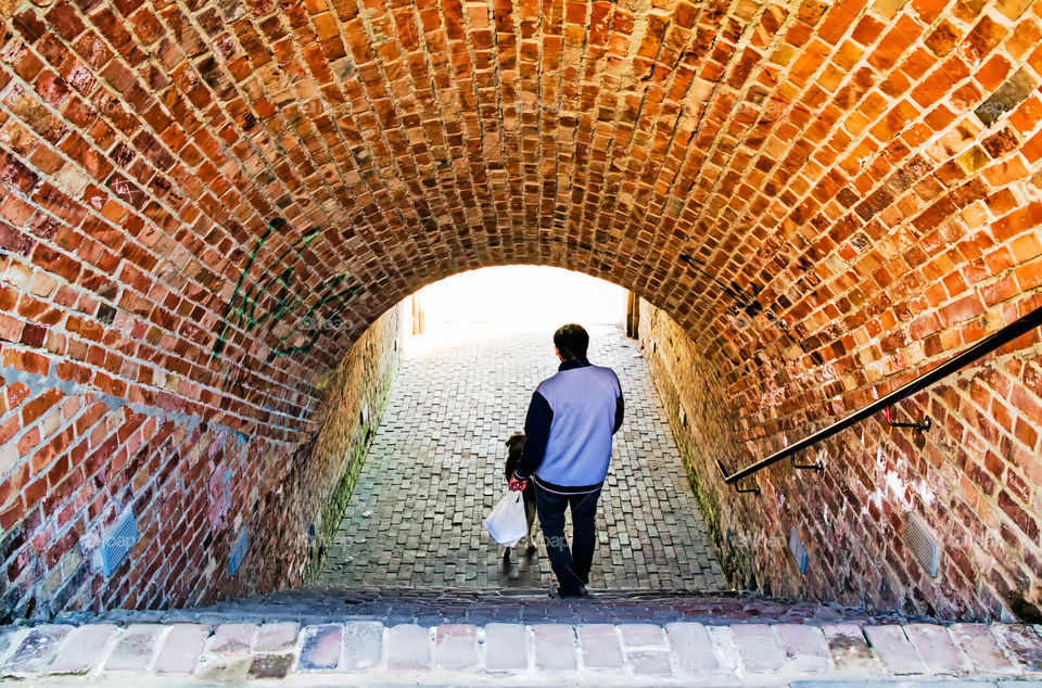 Rear view of man walking in tunnel.