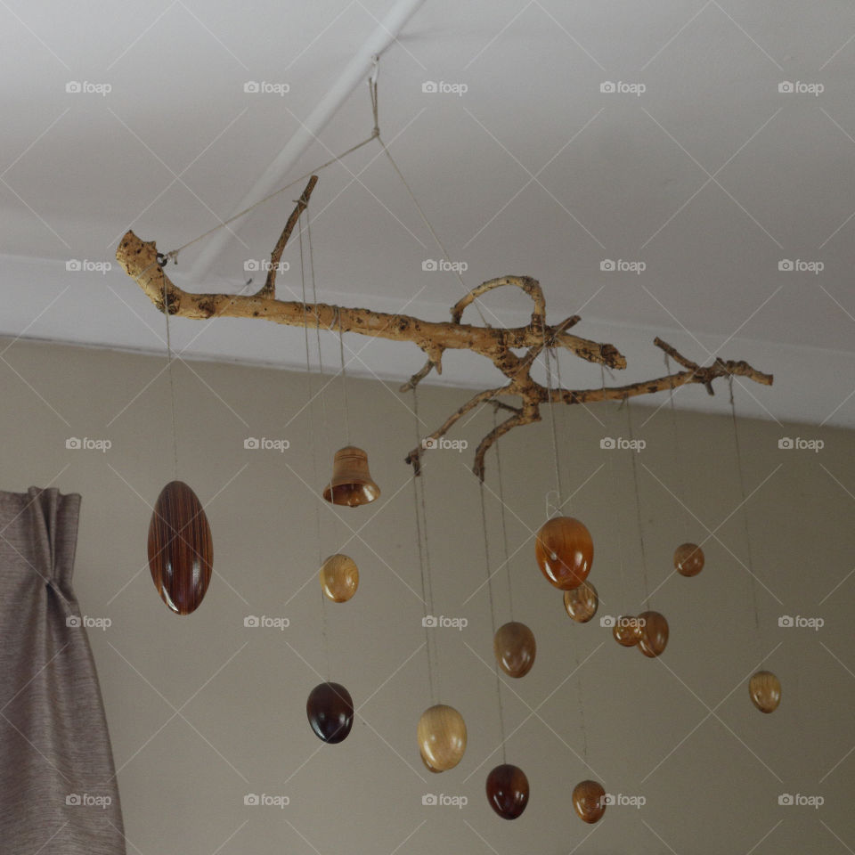 Varnished wooden baubles hung by string from a dry branch - interior decoration