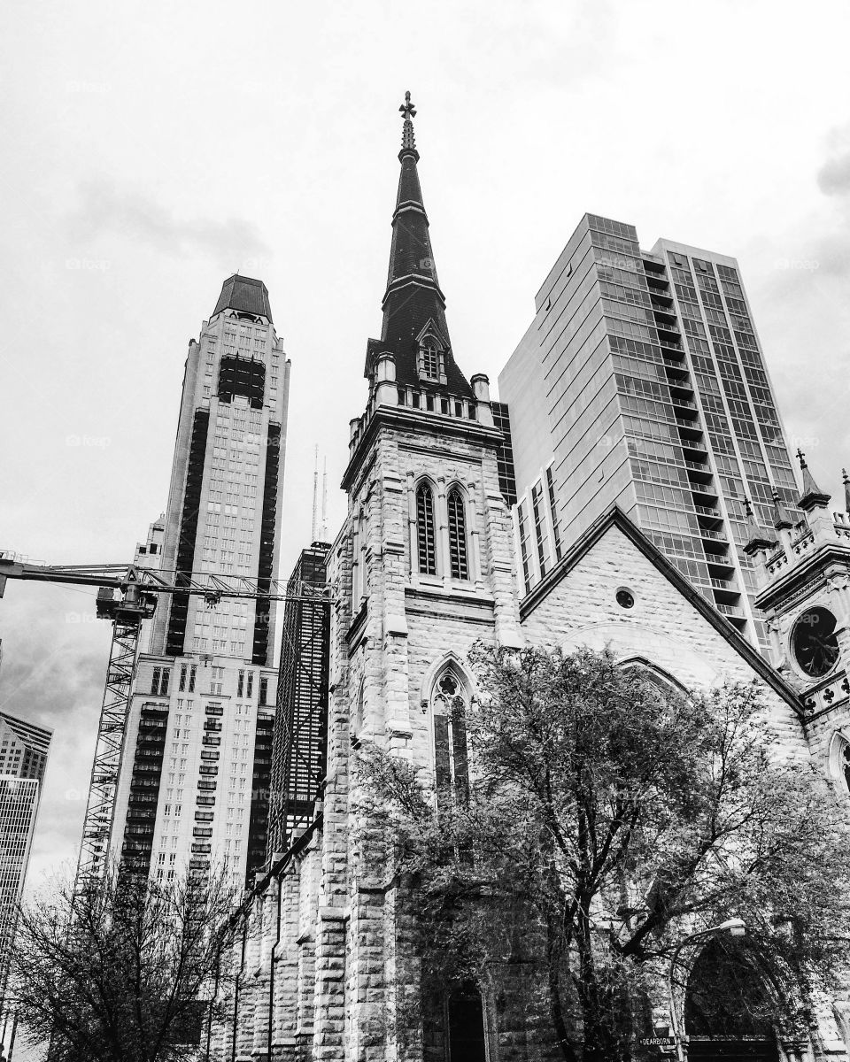 Black and white photo of a church in Chicago. Hancock building is visible in the back. 