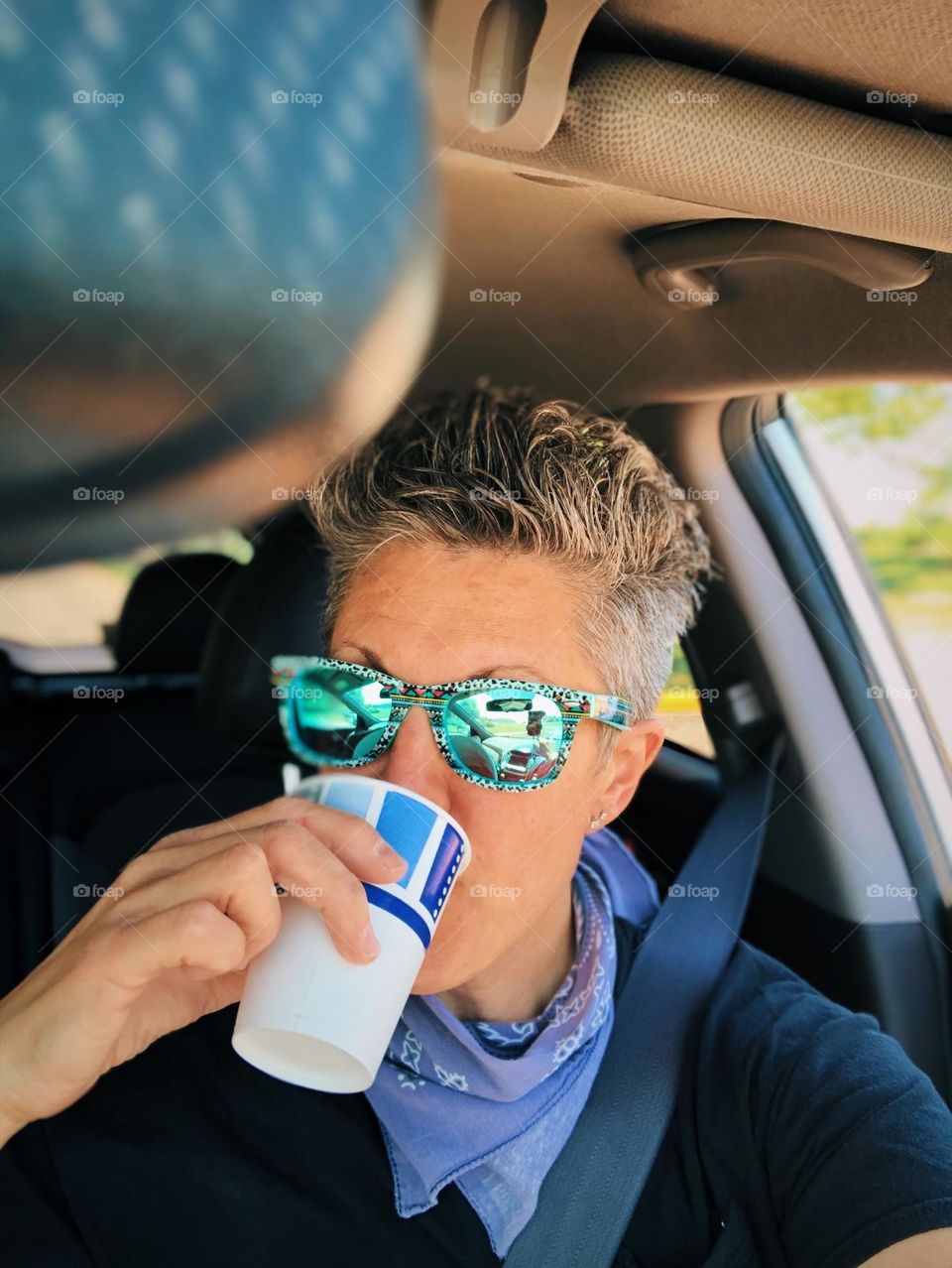 Woman hydrates while driving on a road trip, drinks on the road trip to vacation, woman driving on a road trip, adventurous woman driving and drinking water on a road trip 