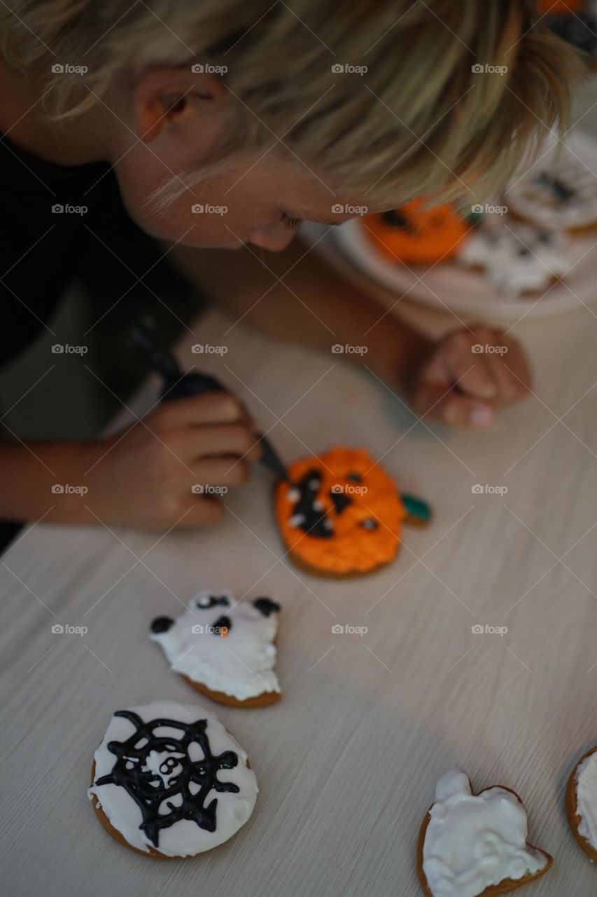 seven year old boy decorating handmade cookies for Halloween