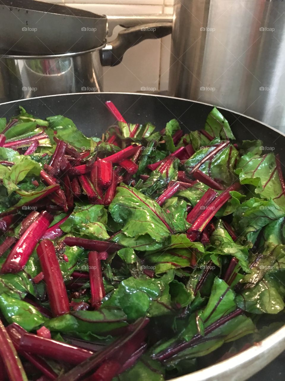 Beetroot leaves leaf greens in cooking pan stovetop closeup healthy cooking 