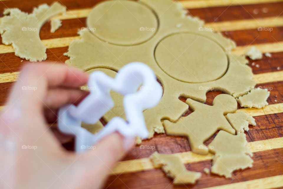 Fun at home means baking time! Image of pressing out men and circle shapes in cookie dough. Hand holding man shaped cookie cutter.