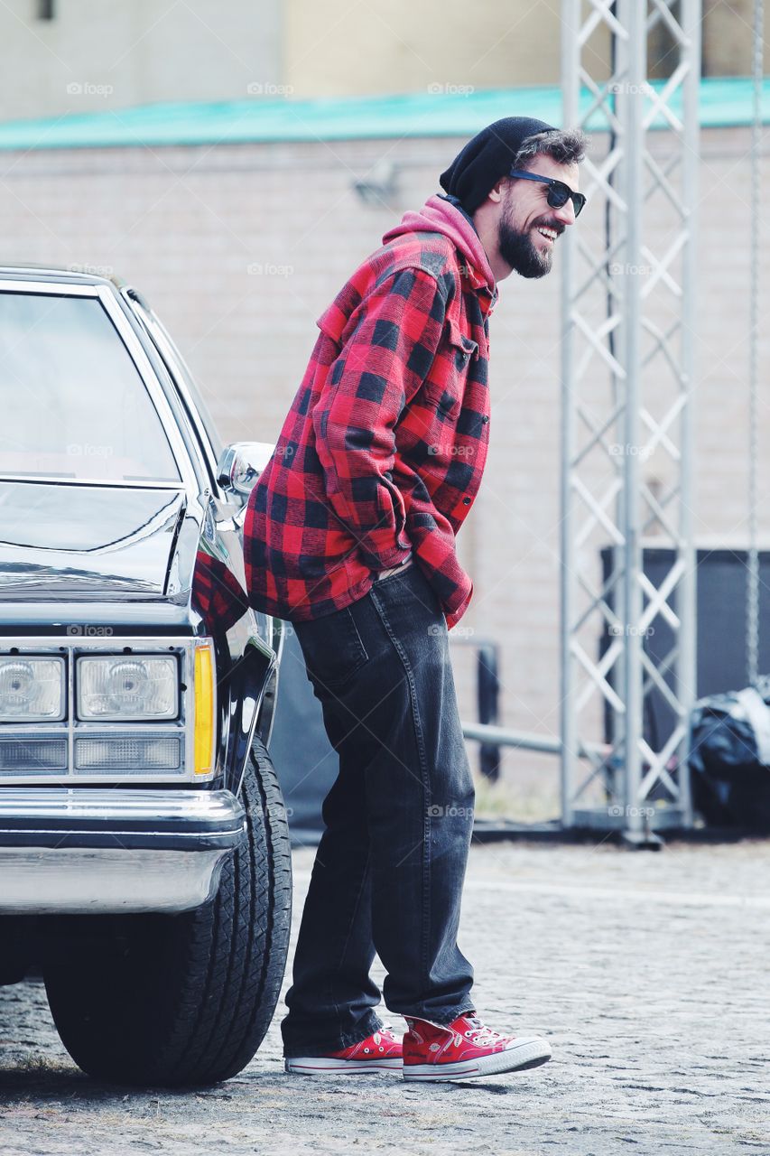 Bearded man in a casual clothes and sunglasses standing near retro car