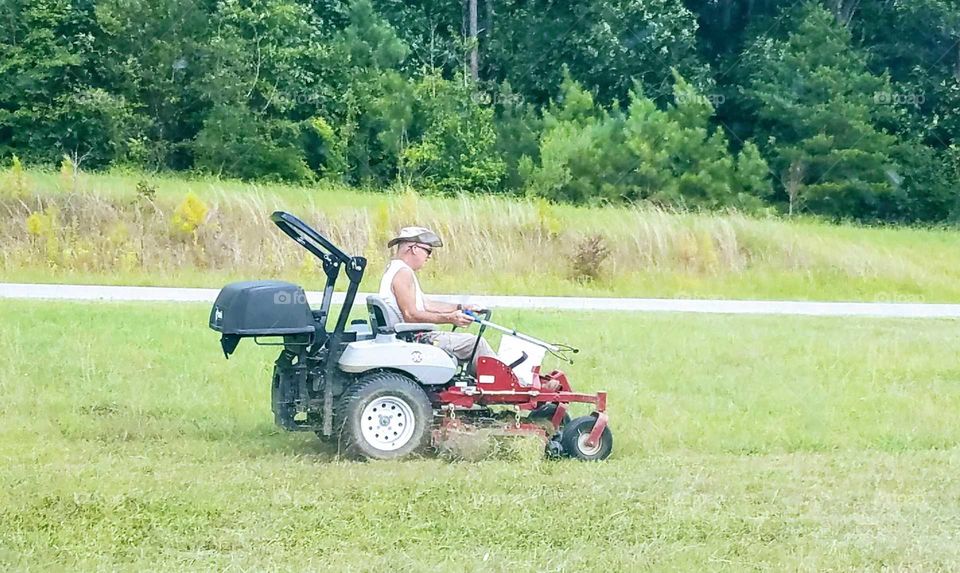 A man mowing a lawn with an industrial size riding lawnmower