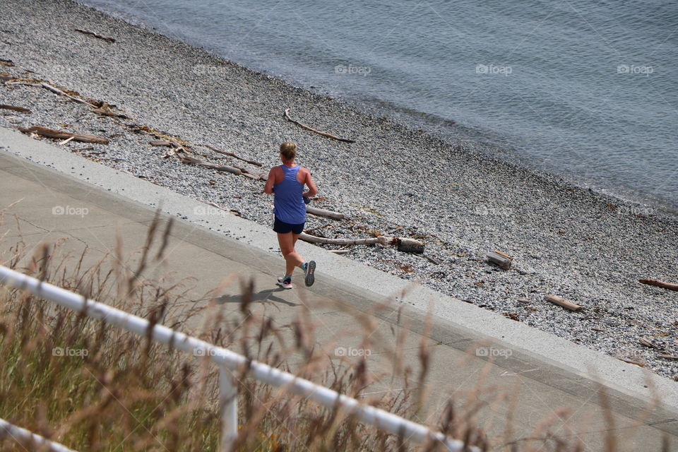 Woman running on the path by the beach on a warm day of June 