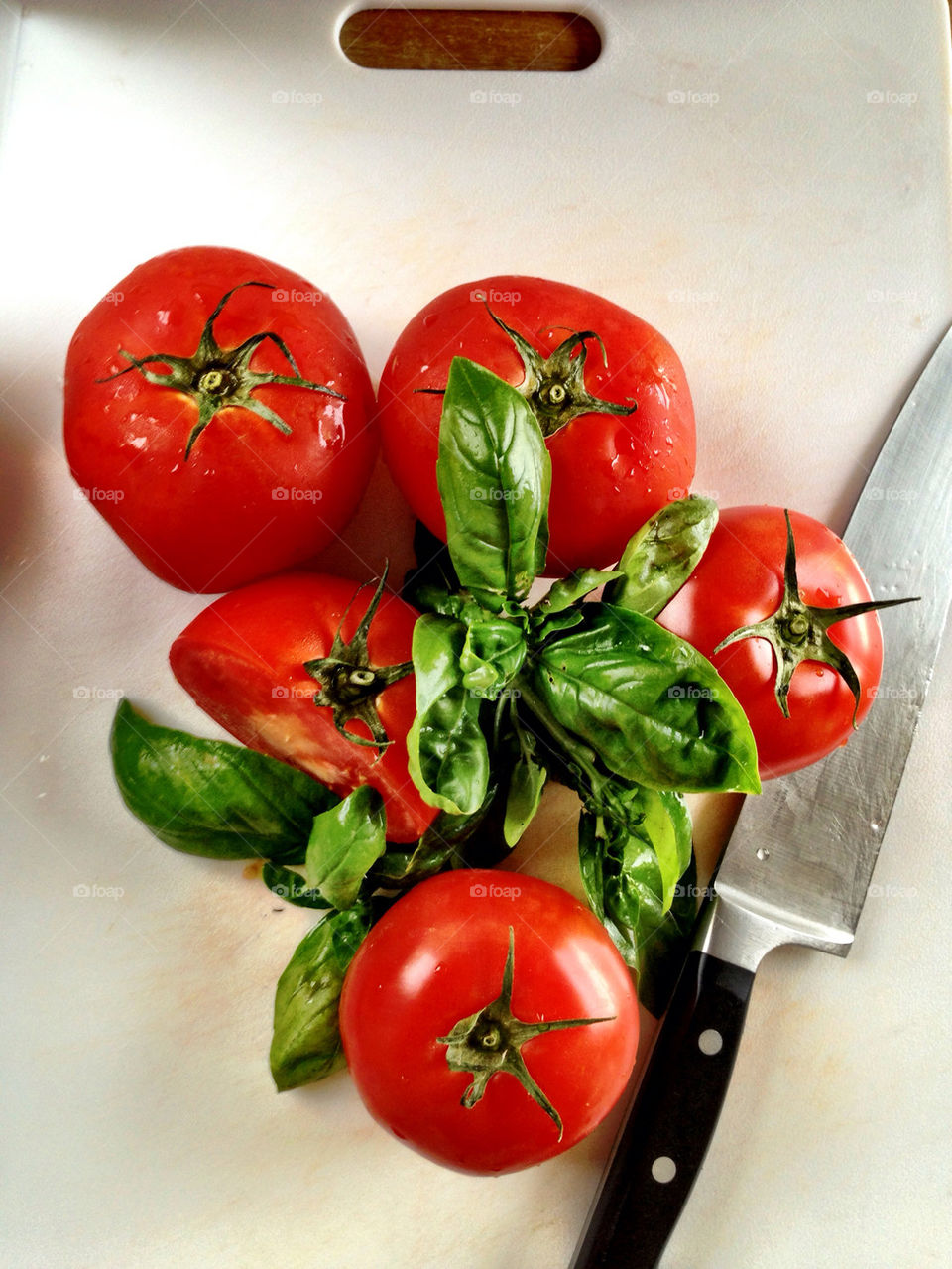 Tomatoes and basil with knife on cutting board