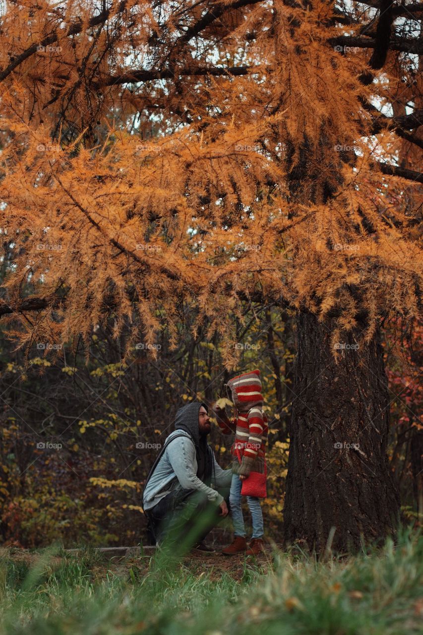 Dad talking to daughter under the autumn tree in the park