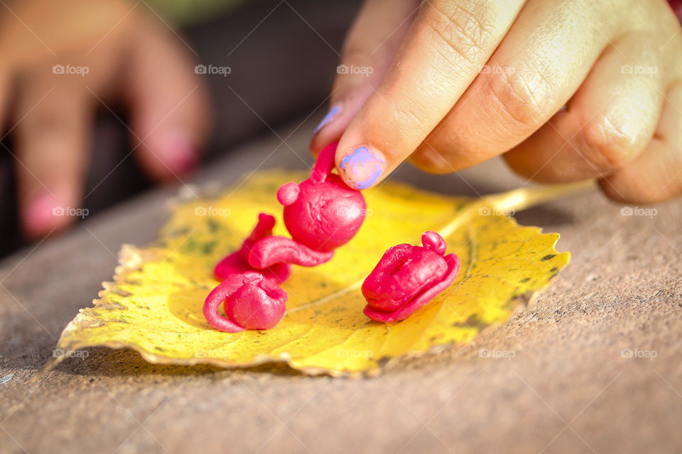 Little girl is playing with a tiny handmade red tea set