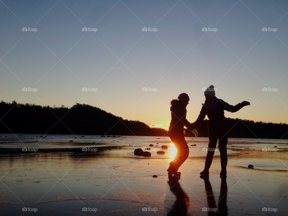 Two girls on ice in the sunset