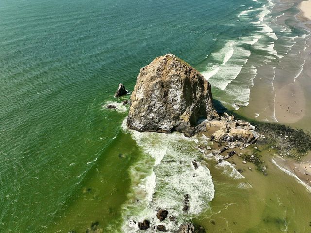 Haystack Rock standing tall amidst the serene beauty of Cannon Beach, where tide pools meet the endless horizon