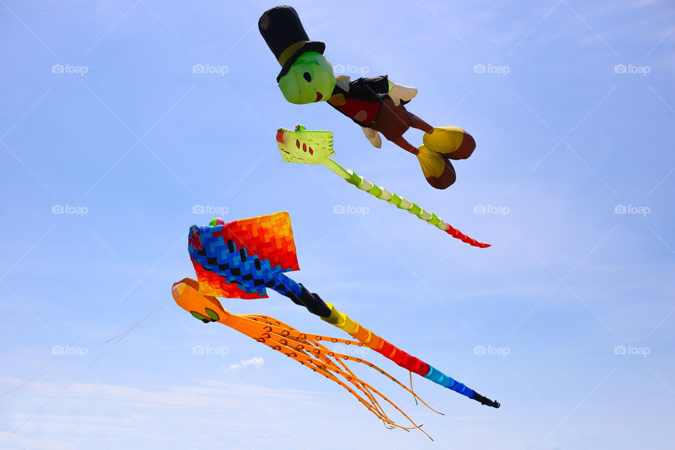 Colorful kites are flying in the blue sky. Kites show