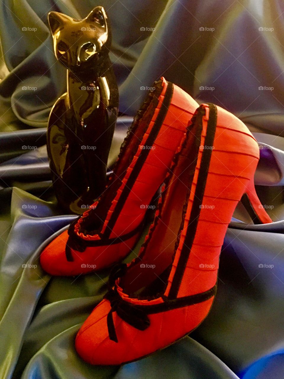 Black cat overlooking sexy red heels. 