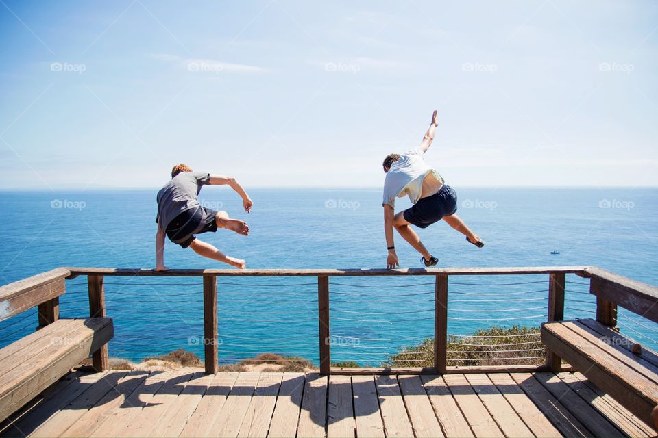 Two people jumping off boardwalk