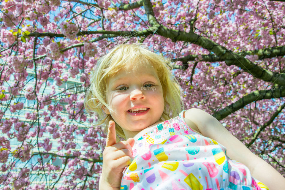 Young girl is playing in the park under a cherry blossom tree in Malmö Sweden.