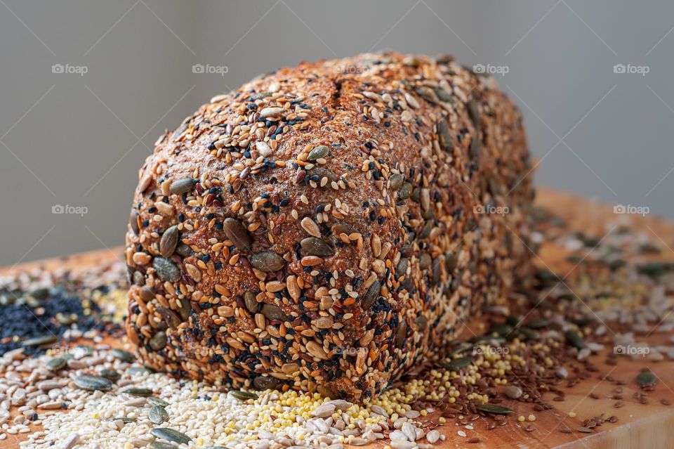 Freshly baked organic loaf of multi-seeded bread on wooden board.