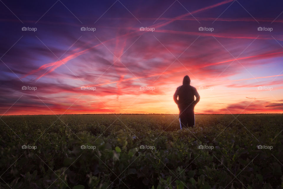 Silhouette standing in field at sunset sunrise with beautiful sky 