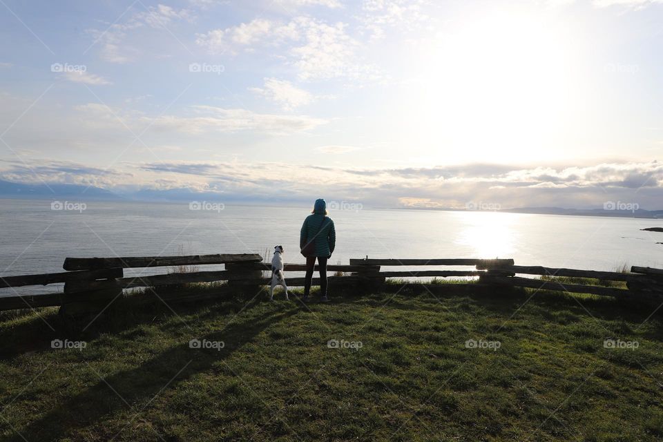 Woman and dog by the coastal fence 