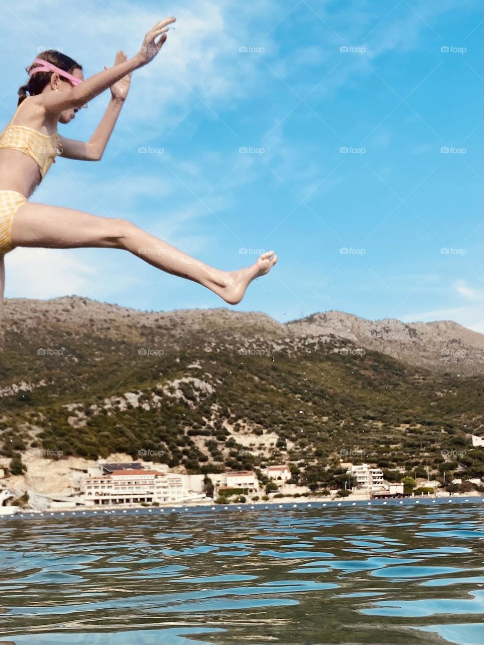 The last lazy days of a summer afternoon. A girl in a yellow bathing suit leaping into the sea.