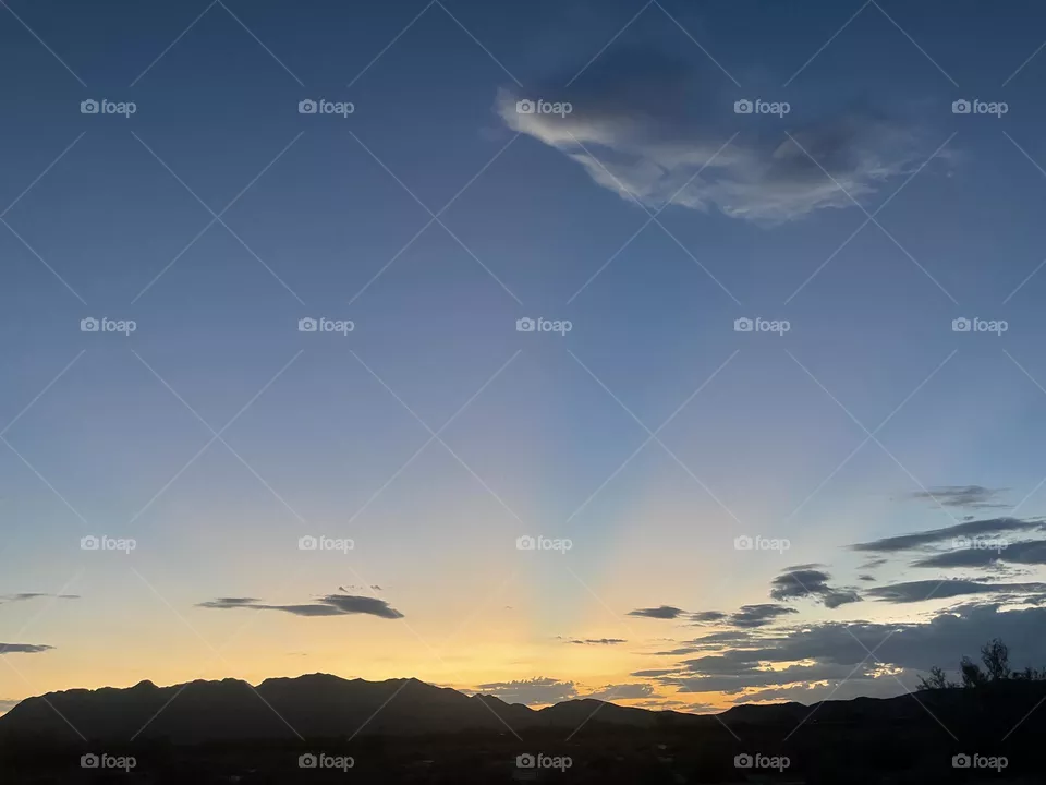 A cloudy and bright sunset with mountains below.  