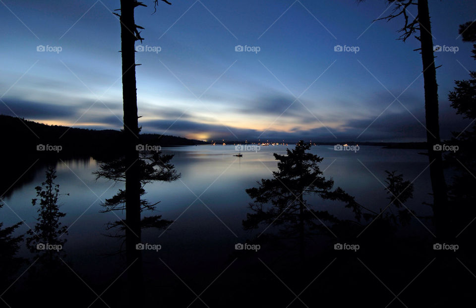 Sun setting over the calm ocean bay with the city lights in the